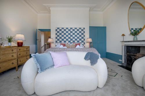 a bedroom with a white chair in front of a bed at Admirals Hard in Budleigh Salterton