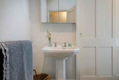 a white bathroom with a sink and a mirror at Admirals Hard in Budleigh Salterton