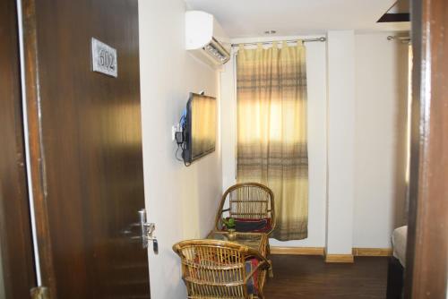 a room with two chairs and a door with a window at Simple & Sustainable- Room with facilities a guest need in Kathmandu