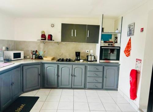 a kitchen with blue cabinets and a white tile floor at Le Domaine de la Chaloupe in Saint-Leu