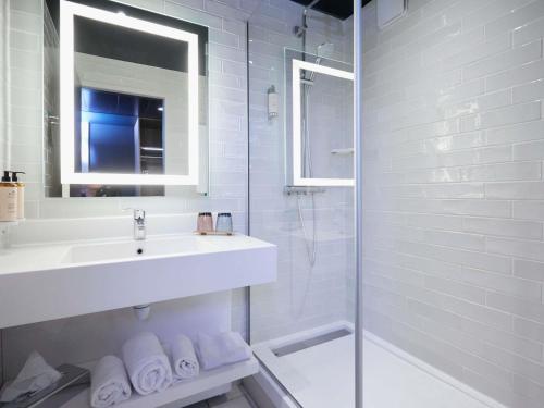 a white bathroom with a sink and a shower at Mercure Arras Centre Gare in Arras