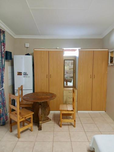 a kitchen with a table and a refrigerator and cabinets at Mossel Bay Self-Catering in Mossel Bay