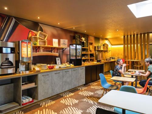 two women sitting at tables in a restaurant kitchen at ibis Saint Dizier in Saint-Dizier