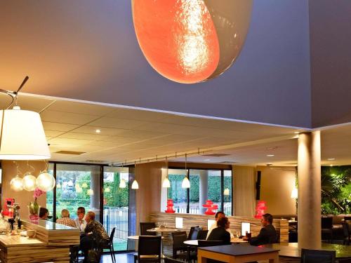 a dining room with people sitting at tables in a restaurant at ibis Europe Chalon Sur Saone in Chalon-sur-Saône