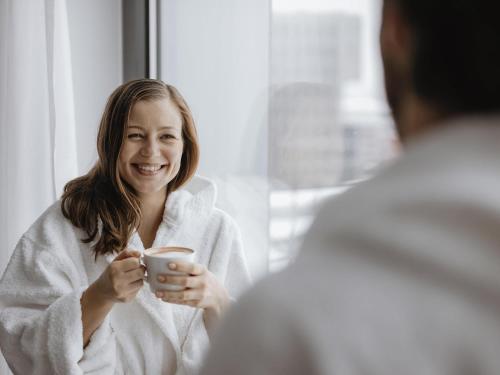 a woman in a bathrobe holding a cup of coffee at ibis Dresden Zentrum in Dresden