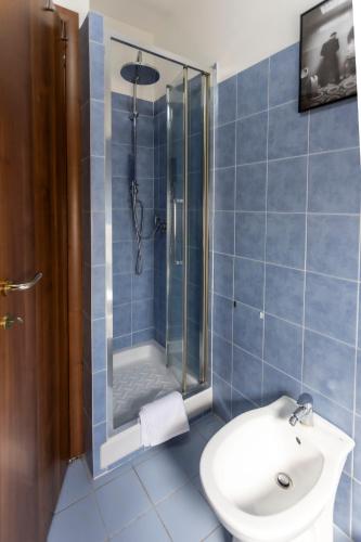a blue tiled bathroom with a shower and a sink at acasadigiò B&B in Rome