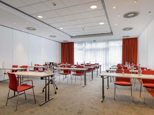 a dining room with tables and red chairs at Mercure Hotel Stuttgart Airport Messe in Stuttgart