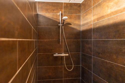 a bathroom with a shower with brown tiles at Oude Dijkje in De Koog