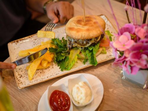a plate with a hamburger and french fries on a table at Mercure Hotel Stuttgart Airport Messe in Stuttgart