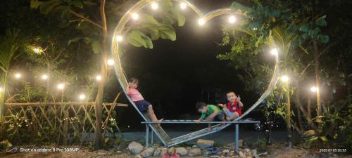 two children sitting on a swing at a park at night at Homestay trọng hiếu in Na Tong