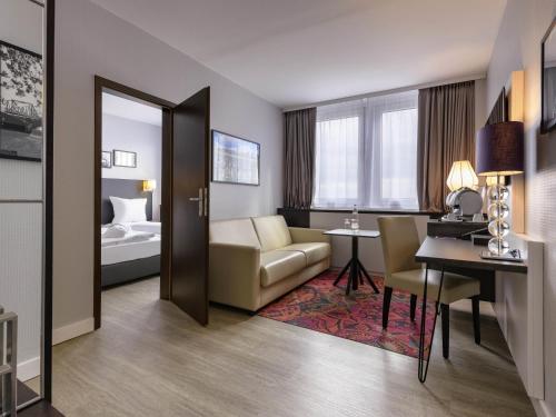 a hotel room with a bed and a living room at Mercure Hotel Potsdam City in Potsdam