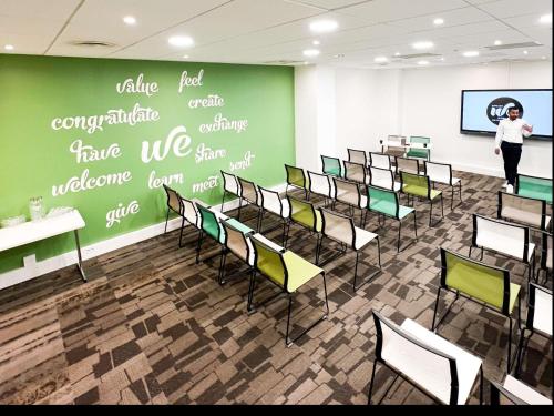 a woman standing in a room with a green wall at Hotel Mercure Toulouse Centre Compans in Toulouse