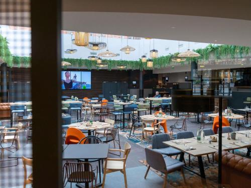a restaurant with tables and chairs and a large window at Hotel Mercure Toulouse Centre Compans in Toulouse