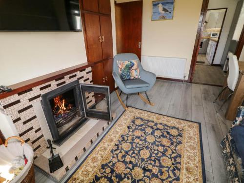 Una sala de estar con una silla y una chimenea. en Loch Illion View, en Meenmore