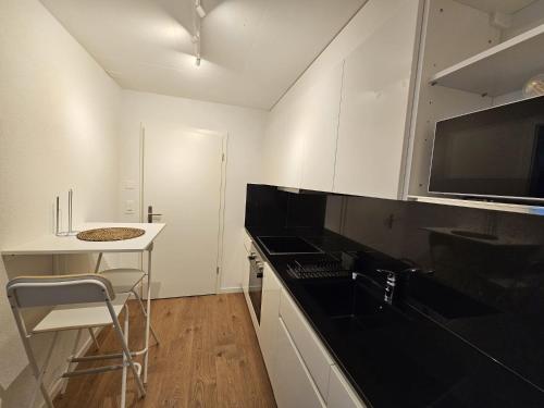 a kitchen with white cabinets and a black counter top at Cosy private room in Lausanne center in Lausanne