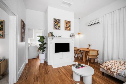 a white living room with a couch and a tv at The Piccolo Cottage in Hobart