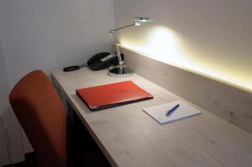 a desk with a lamp and a notebook and a pen at Hotel Restaurant Bellevue au Lac in Thun