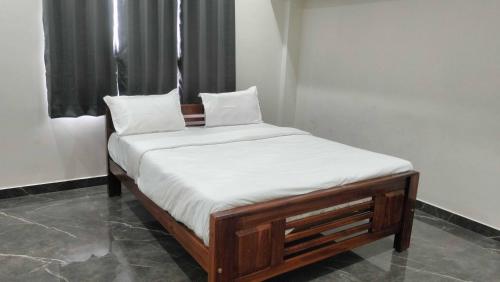 a bed with white sheets and pillows on it at Collection O Nandagokula Convention Centre Formerly Arasu Comforts in Hassan