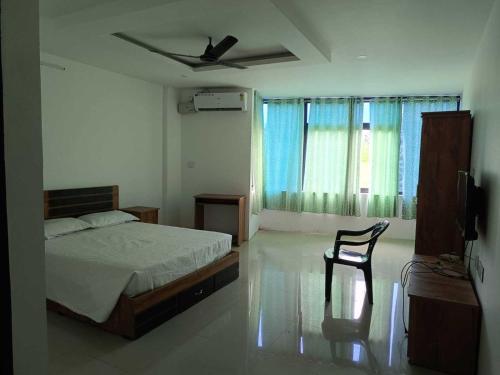 Un dormitorio con una cama y una silla y una ventana. en Hotel O Erumeli Bus Terminal Kottayam Formerly Pious B Residency, en Erumeli