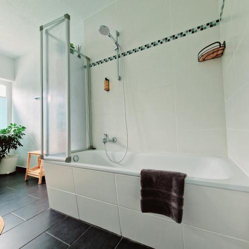 a white bathroom with a shower and a tub at Holle - Land Holidays, parterre Ferienwohnung in Lichtenau