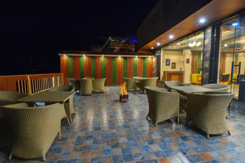 a restaurant with tables and chairs and a fire at Hotel Pawan Regency- Best Mountain View Hotel In McLeodganj in McLeod Ganj