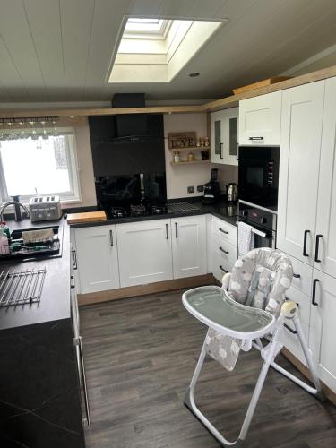 a kitchen with white cabinets and a chair in it at Blissful Lodge Haven Lakeland in Flookburgh