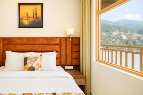 a bedroom with a bed and a large window at Hotel Pawan Regency- Best Mountain View Hotel In McLeodganj in McLeod Ganj
