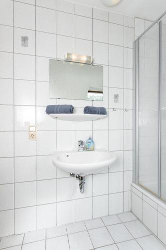 a white bathroom with a sink and a mirror at Reit- und Ferienhof Maack in Neuharlingersiel