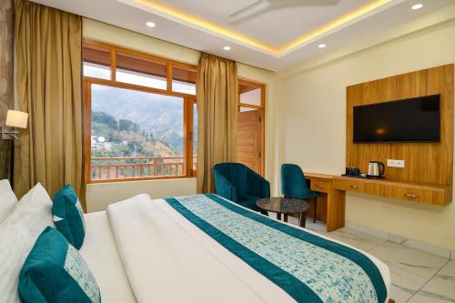 a hotel room with a bed and a desk and a window at Hotel Pawan Regency- Best Mountain View Hotel In McLeodganj in McLeod Ganj