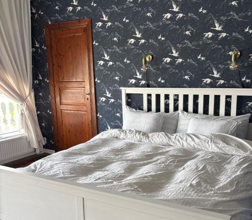 a bed in a bedroom with a black and white wallpaper at Annas gård, stall & pensionat in Fjärås