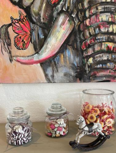 a table with two glass jars and a painting of a butterfly at Annas gård, stall & pensionat in Fjärås