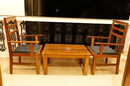 two wooden chairs and a wooden table and bench at Broad Bean Royal Resort Goa in Canacona