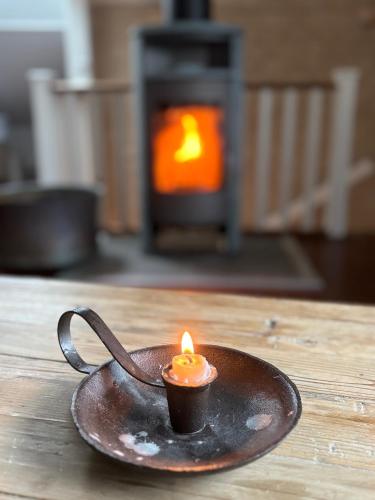 a small candle in a cup on a table with a fireplace at Annas gård, stall & pensionat in Fjärås