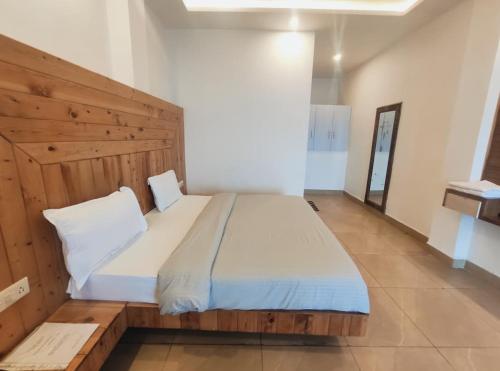 a bedroom with a large bed with a wooden headboard at Voga View Hotel and Restro in Mussoorie