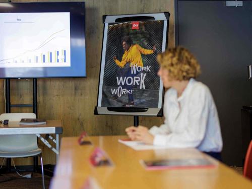 a woman sitting at a table in front of a screen at ibis Toulon La Valette in La Valette-du-Var