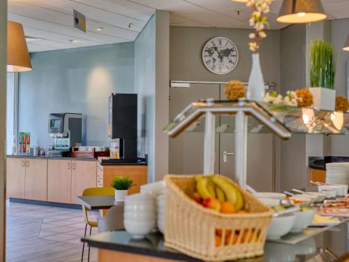 a room with a table with a basket of fruit at ibis Hotel Frankfurt Messe West in Frankfurt