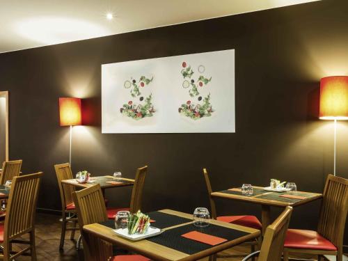 a dining room with tables and chairs and a painting at Hotel ibis Faro Algarve in Faro