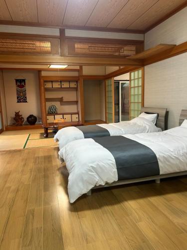 a bedroom with two large beds with white sheets at アットホーム五島 in Goto