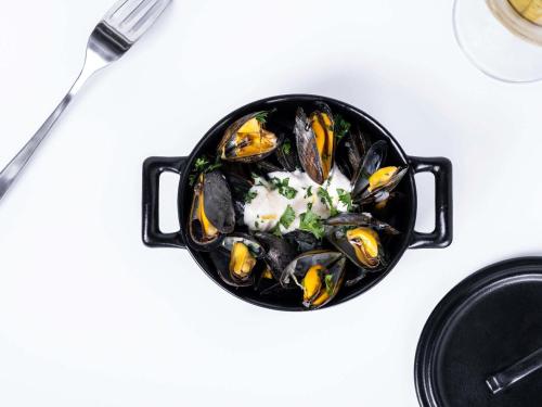 a black bowl of mussels on a white table at Mercure Compiègne Sud in Compiègne
