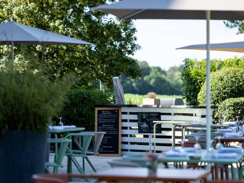 an outdoor patio with tables and umbrellas and chairs at Mercure Compiègne Sud in Compiègne