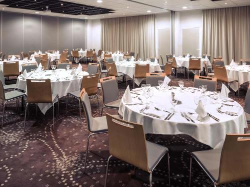a banquet room with tables and chairs with white tablecloths at Mercure Compiègne Sud in Compiègne