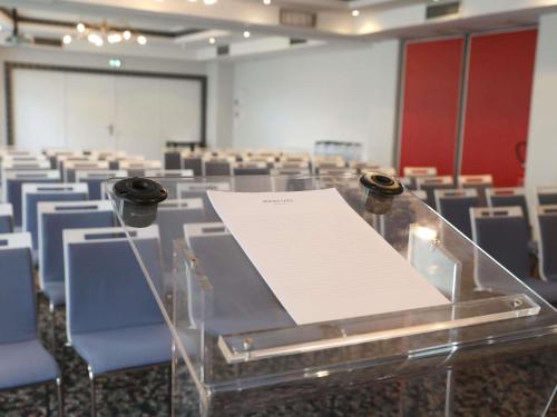a conference room with chairs and a table with a paper at Hôtel Mercure Lyon Centre Charpennes Parc de la Tête d'Or in Villeurbanne
