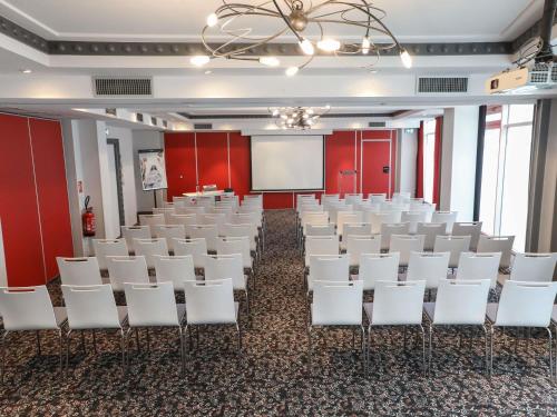 a conference room with white chairs and a whiteboard at Hôtel Mercure Lyon Centre Charpennes Parc de la Tête d'Or in Villeurbanne