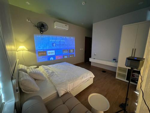 - une chambre avec un lit et un grand écran dans l'établissement Núi Homestay Huế, à Hue