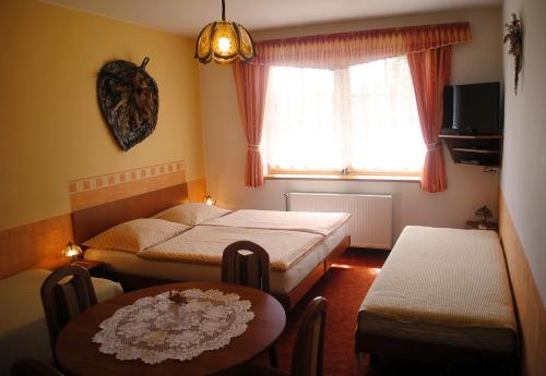 Habitación con 2 camas, mesa y ventana en Pension B&B, en Vrchlabí