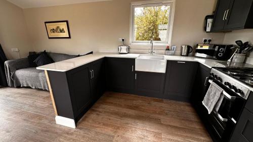a kitchen with black cabinets and a sink and a couch at Entick Lodge No 4 in Dunswell