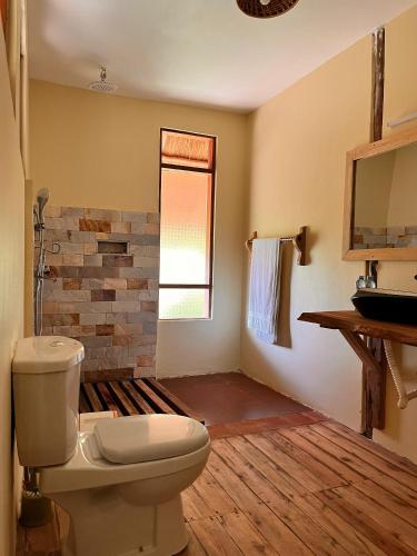 a bathroom with a toilet and a window at Tabingi Safari Lodge in Katunguru