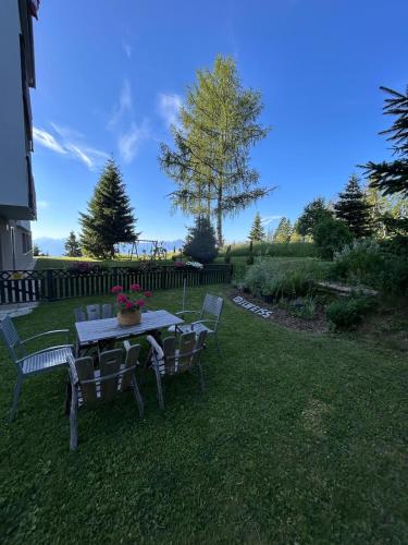 a table and chairs in a yard with a table and flowers at Appartement Wolke7 byTILLY - Im Skigebiet Gerlitzen auf 1500m Seehöhe - familienfreundliche 3 Zimmer Wohnung - Hallenbad im Haus - moderne Küche mit Vollausstattung - Balkon - traumhafte Aussicht über ganz Kärnten - himmlisch bequeme Boxspringbetten in Treffen