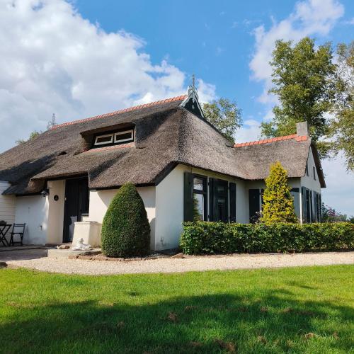a house with a thatched roof and a yard at Tuinkamer 't Strunerke in Augustinusga