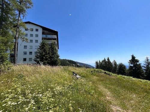 a building sitting on top of a grassy hill at Appartement Wolke7 byTILLY - Im Skigebiet Gerlitzen auf 1500m Seehöhe - familienfreundliche 3 Zimmer Wohnung - Hallenbad im Haus - moderne Küche mit Vollausstattung - Balkon - traumhafte Aussicht über ganz Kärnten - himmlisch bequeme Boxspringbetten in Treffen
